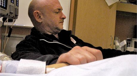 Mark Kelly drí za ruku svojí manelku a senátorku Gabrielle Giffordsovou v tucsonské nemocnici. (9. ledna 2011)