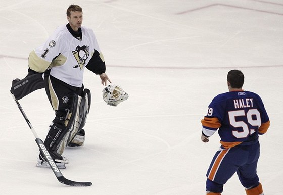 Micheal Haley (vpravo) z NY Islanders vykává s ím vyrukuje branká Pittsburghu Brent Johnson.