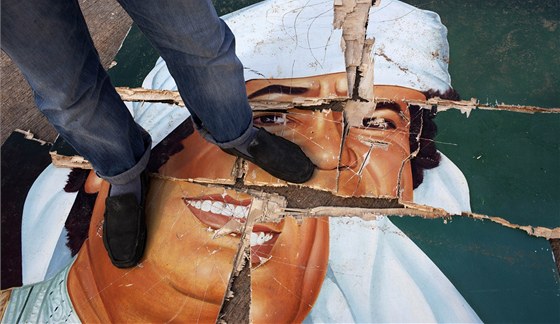 Libyjec stojí na znieném portrétu Muammara Kaddáfího (24. února 2011)