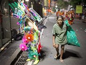 ena sbrajc v ulicch brazilskho Ria odpadky, prochz kolem jednoho z umlc pipravujcch se na vystoupen ve slavnm karnevalovm prvodu. (7. bezna 2011)