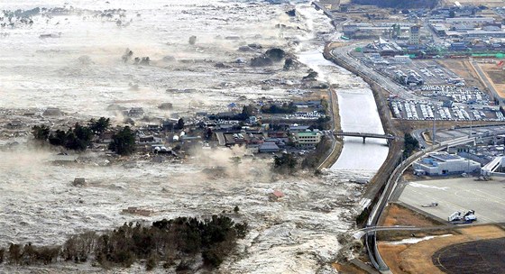 Niivá pívalová vlna se valí na japonské pobení msto Iwanuma. (11. bezna 2011)
