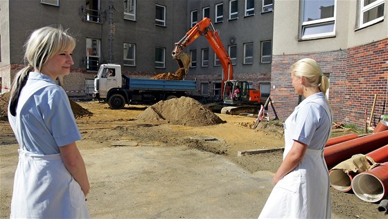 Zdravotní sestry sledují bagr p rekonstrukci v chebské nemocnici.