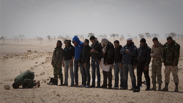 Libyjtí povstalci utíkají ped stelami z minomet Kaddáfího jednotek.