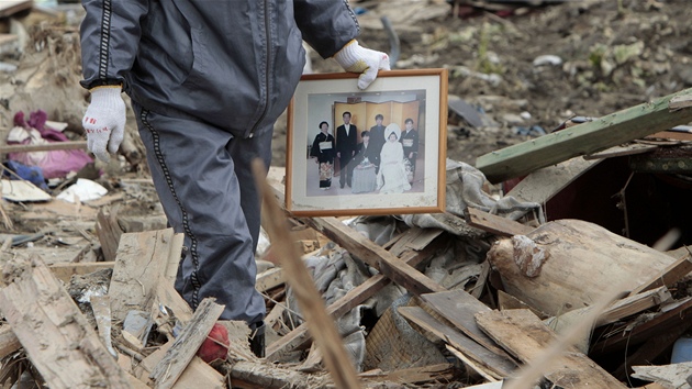 Toii Obata si nese rodinnou fotografii, kterou zachránil ze svého domu v Natori, který zdemolovalo zemtesení a tsunami (20. bezna 2011)