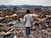 Mu se dv na zdevastovan japonsk msto Kesennuma, kter smetla niiv vlna tsunami. (30. bezna 2011)