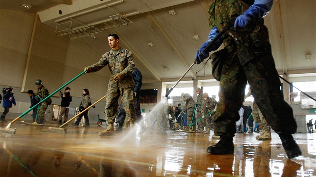 Amerití a japontí vojáci istí nánosy bahna v tlocvin gymnázia v japonském mst Iinomaki. (30. bezna 2011)