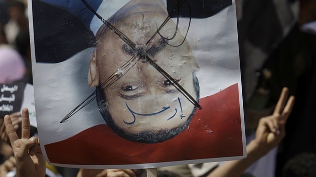 Demonstranti drí transparent s pekrtnutým portrétem prezidenta Sáliho 