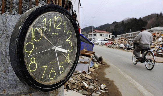 Mu na kole projídí kolem hodin zastavených pi tsunami v japonském mst Miyako. (11. dubna 2011)