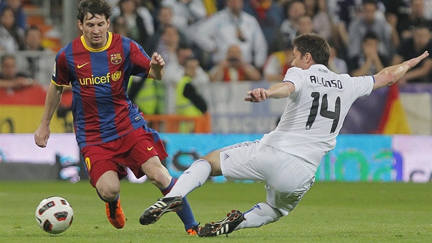 VEDLE! Barcelonský Lionel Messi (vlevo) obchází s míem Xabiho Alonsa z Realu Madrid.