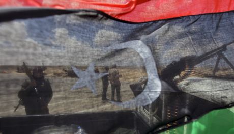 Rebelové jsou vidt skrze bývalou libyjskou vlajku u msta Adedábíja (21. dubna 2011)