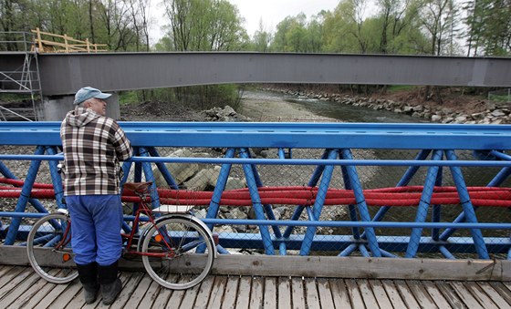 Mu sleduje z provizorní lávky stavbu nového mostu pes Ostravici.