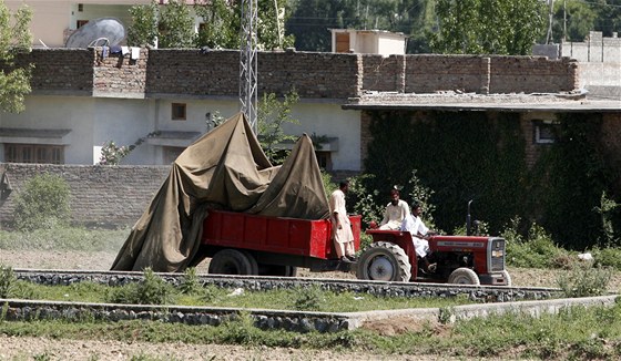 Pákistánci odváejí zakryté trosky vrtulníku, který se porouchal pi operaci
