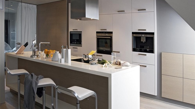 Puristicky bílá pracovní deska je vyrobená ze speciálního materiálu Kerrock. Kuchyské zázemí spluje vechny ergonomické poadavky. Úloné prostory mají navíc integrované osvtlení pro vtí pehlednost.
