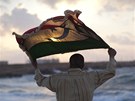 Obyvatel Benghz s vlajkou Libye z dob monarchie (11. kvtna 2011)