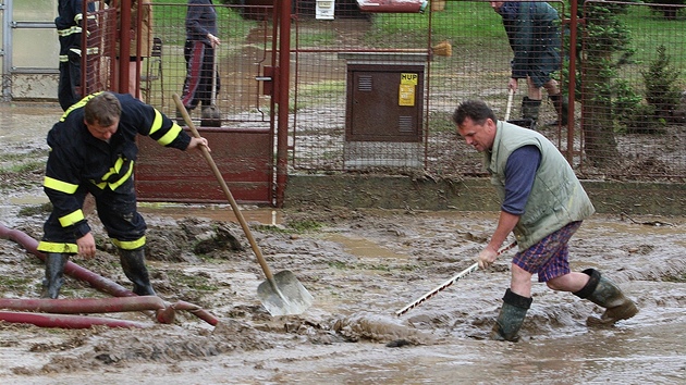 Obyvatelé obce Úlice a hasii odklízejí nánosy bahna po prudké bouce.