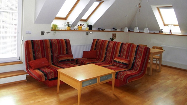 Dominantou bytu je obývací pokoj s krbem, piznaným trámovím a oteveným prostorem celé stechy.