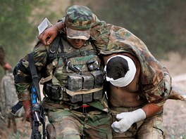 Kandahár, Afghánistán. Afghánský voják nese svého kamaráda zranného pi výbuchu náloe nastraené Talibanem k vrtulníku americké armády.