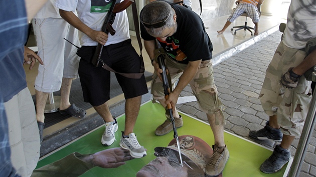 Libyjtí rebelové strhávají portréty a plakáty Muammara Kaddáfího. (23. srpna