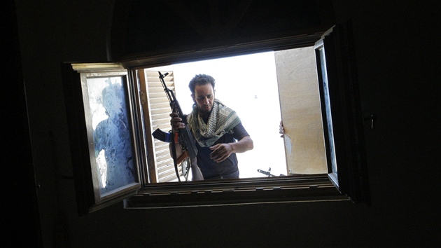 Libyjský povstalec kouká oknem do domu Saadiho Kaddáfího (24. srpna 2011)