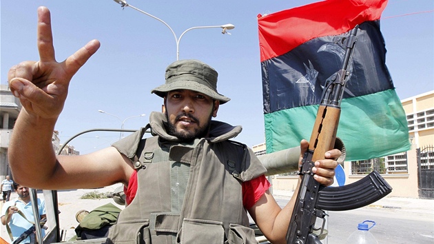 Rebel v Kaddáfího rezidenci ukazuje znak vítzství. (24. srpna 2011)