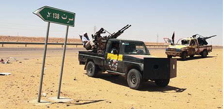 Vozy libyjských rebel jsou zaparkované vedle silniního ukazatele na msto