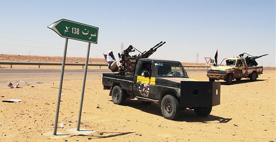 Vozy libyjských rebel zaparkované poblí silniního ukazatele na Syrtu.
