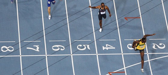 S POHODLNÝM NÁSKOKEM. Usain Bolt probíhá cílem závodu na 200 m, soupei