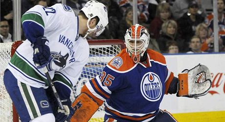 Gólman Edmontonu Dwayne Roloson elí nájezdu Daniela Sedina z Vancouveru.