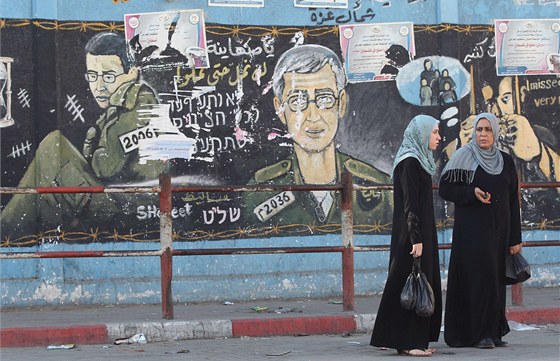 Palestinky kráí v pásmu Gazy kolem zdi, na ní je vyobrazen izraelský voják