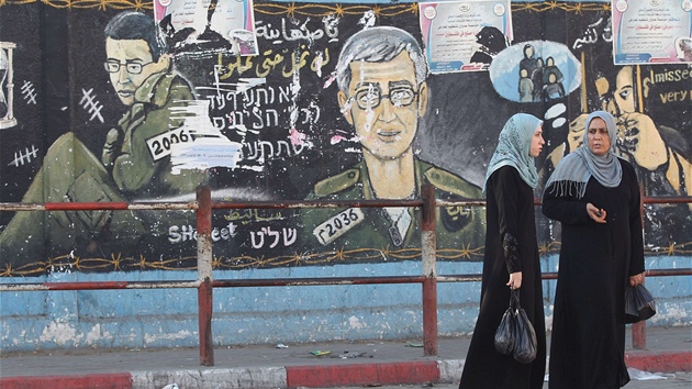 Palestinky kráí v pásmu Gazy kolem zdi, na ní je vyobrazen izraelský voják