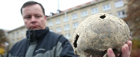 Policejní vyetovatel Michal Laka ukazuje lebku jedné z údajných obtí pováleného násilí, kterou spolu s dalími ostatky vykopali na louce Budínka u Dobronína na Jihlavsku.