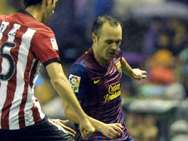 SLALOM V DETI. Andrs Iniesta z Barcelony klikuje mezi fotbalisty Athltika