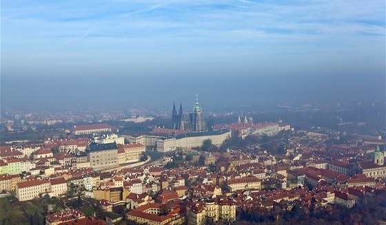 Praský hrad se koupe ve slunením svitu, zatímco zbytek Prahy zahaluje smog a