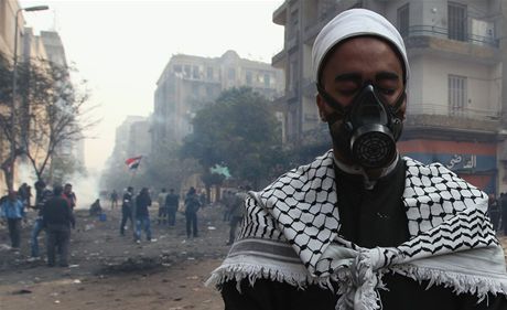 Egyptský duchovní se modlí zatímco protestující prchají ped slzným plynem,