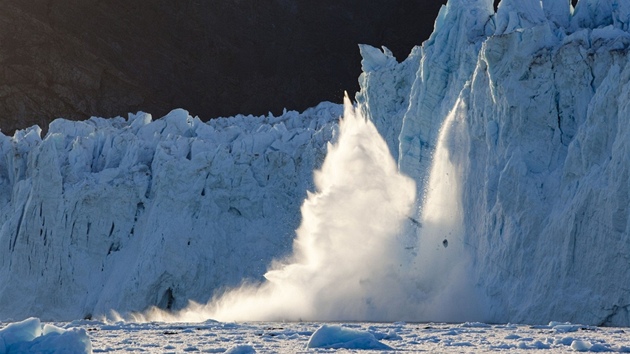 Zapadající slunce ozařuje pukající ledovec a následnou vlnu v zálivu Disko Bay Zapadající slunce ozařuje pukající ledovec a následnou vlnu v zálivu Disko Bay