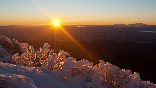 Vchod slunce pobl vrcholu. Vpravo na obzoru je vidt linie sopek v NP Tongariro.