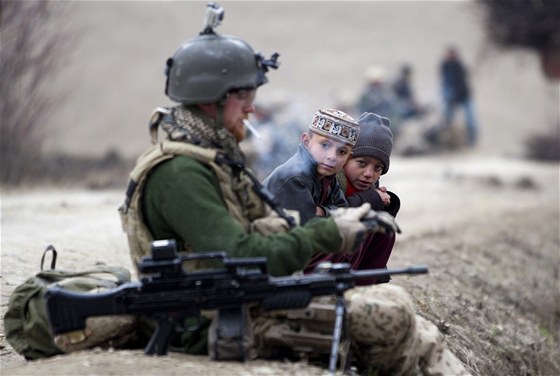 Malí Afghánci pozorují hlídkujícího nmeckého vojáka bhem pauzy na cigaretu....