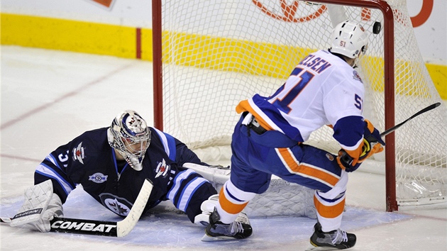 Branká Winnipegu Ondej Pavelec kouká pod nohy Franse Nielsena z NY Islanders,