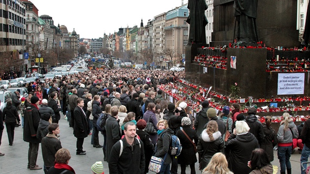 Lidé drí minutu ticha u sochy na Václavském námstí v Praze. (23. prosince