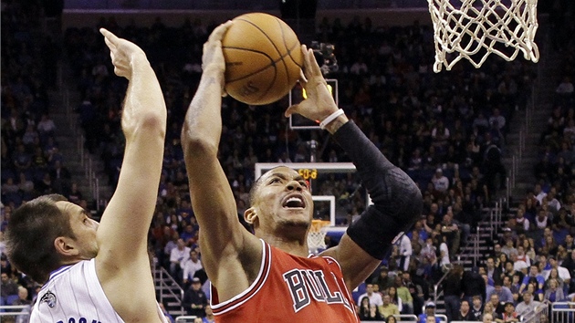 Derrick Rose (v červeném) z Chicaga útočí na koš Orlanda kolem Ryana Andersona. Derrick Rose (v červeném) z Chicaga útočí na koš Orlanda kolem Ryana Andersona.