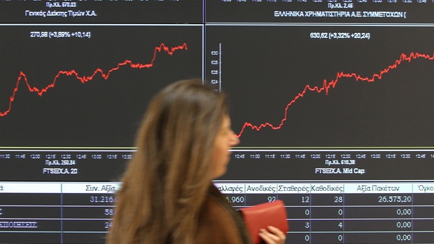 Zaměstnankyně aténské burzy prochází kolem monitorů zaznamenávajících růst Zaměstnankyně aténské burzy prochází kolem monitorů zaznamenávajících růst