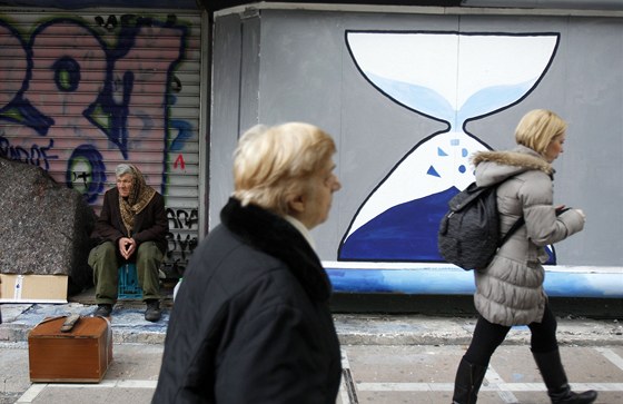 Atéané procházejí kolem graffiti pesýpacích hodin. Ministi financí dnes