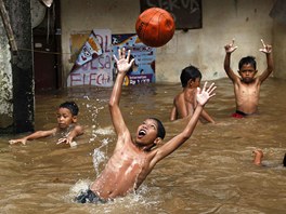 Dti si hrají s míem v zaplavených tvrtích indonéské Jakarty. 