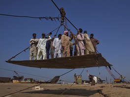 Pákistántí dlníci vyráí na improvizované lanovce na palubu lodi, aby ji