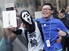 Mladík v masce slaví spolen s páteli ped prodejnou Apple v Tokiu nákup nové