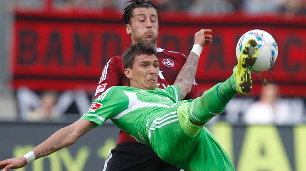 Fotbalista Mario Mandukic z Wolfsburgu (v zeleném) odkopává mí v bundesligovém