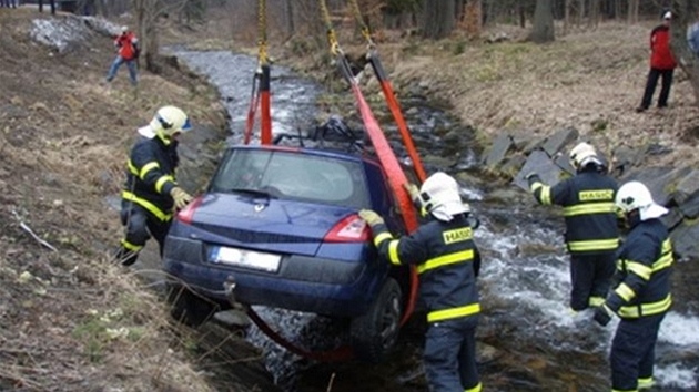 Hasii vytahují Renault Mégane z potoka v Karlov Studánce.