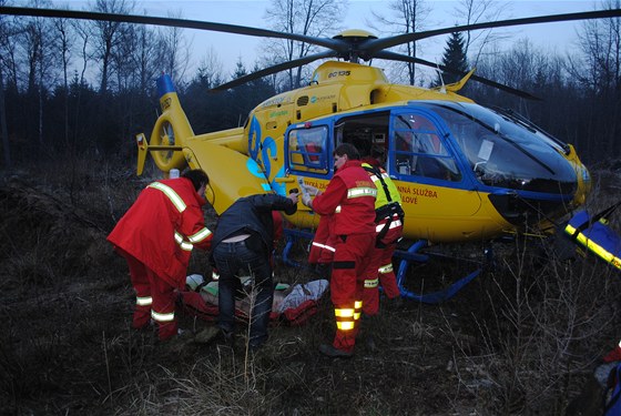 Záchranái nakládají do vrtulníku mue popáleného pi poáru v Javorné na