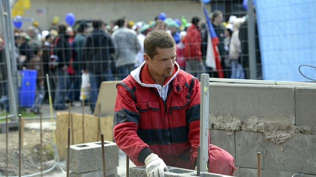 Odborái procházejí v Praze kolem pracujícího dlníka bhem pesunu na místo