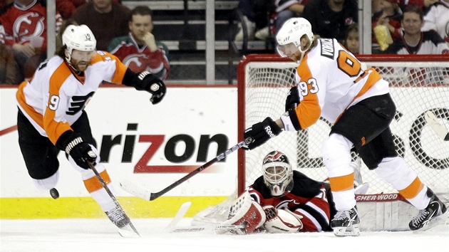 Martin Brodeur v brance New Jersey vyráí puk ped duem Scott Hartnell (vlevo)